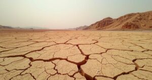 A parched landscape with a cracked soil under a dusty sky reflects the water scarcity in Sudan.