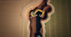 Excavator digging trench on poultry farm due to outbreak containment, Brazil, precise aerial view, earth tones.