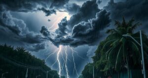 A stormy sky with dark clouds and flashes of lightning alongside heavy rain and hail on a tree-lined street.